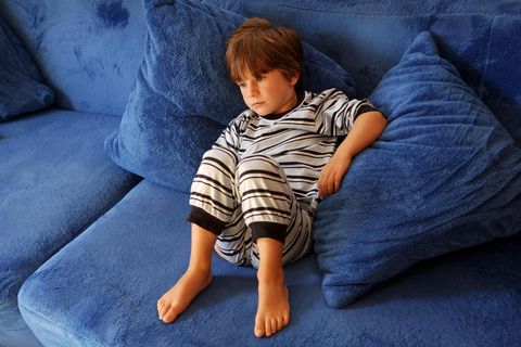 Junge im Schlafanzug liegt auf dem Sofa
