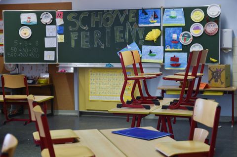 Leeres Klassenzimmer, Stühle sind hochgestellt, an der Tafel steht "Schöne Ferien".