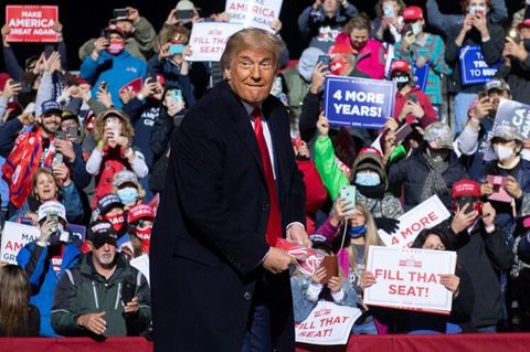 Trump wirft Maske bei Wahlkampfveranstaltung weg, im Hintergrund viele Anhänger ohne Maske zu sehen.