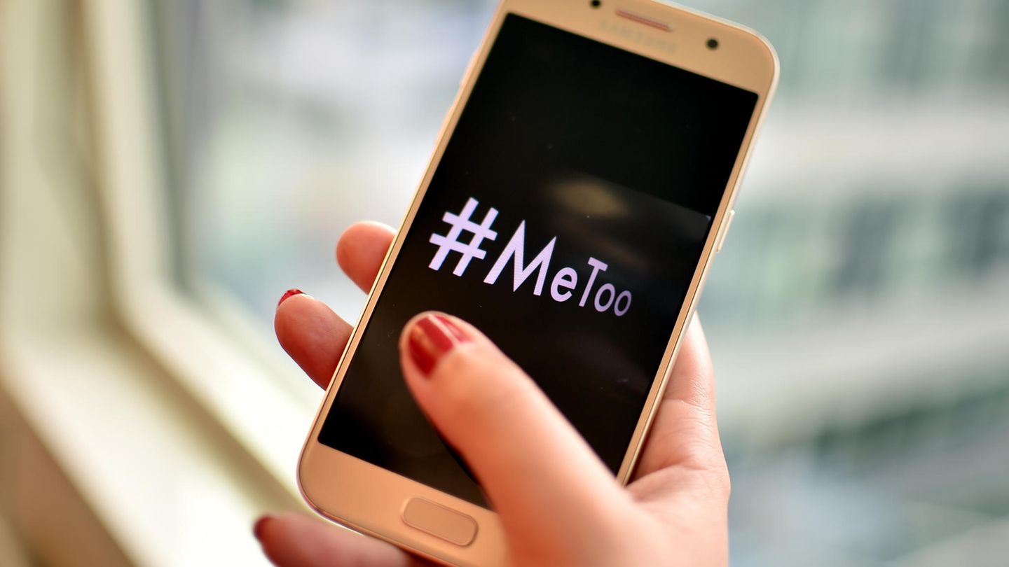 Eine junge Frau hält ein Smartphone mit dem Hashtag "#MeToo" in der Hand