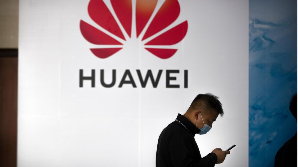 Ein Mann geht an einer Huawei-Werbetafel auf einer Expo vorbei