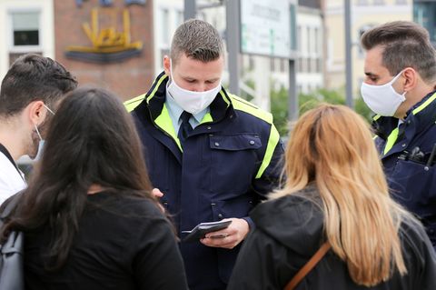 Beamte kontrollieren in Hamburg die Maskenpflicht und stellen Strafe aus.