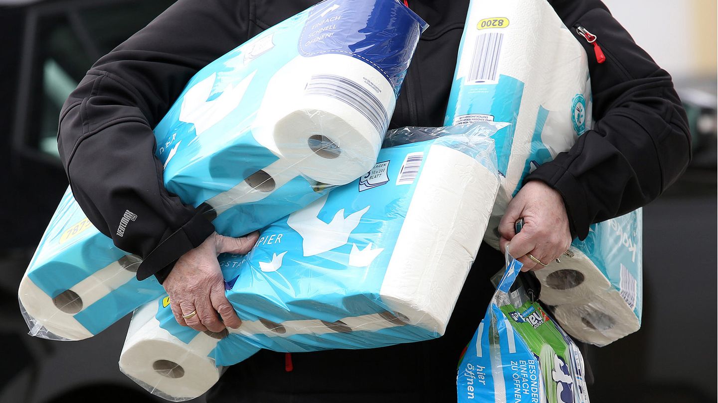 Ein Mann hat den ganzen Arm voller Packungen Toilettenpapier