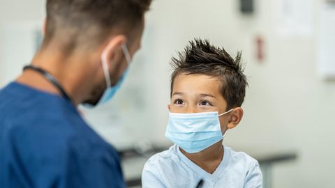 Junge mit Maske in Arztpraxis