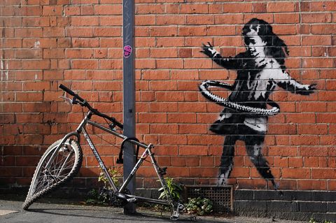 Kunstwerk von Banksy in Nottingham: Ein Mädchen spielt mit Hulla-Hoop-Reifen, davor liegt ein kaputtes Fahrrad