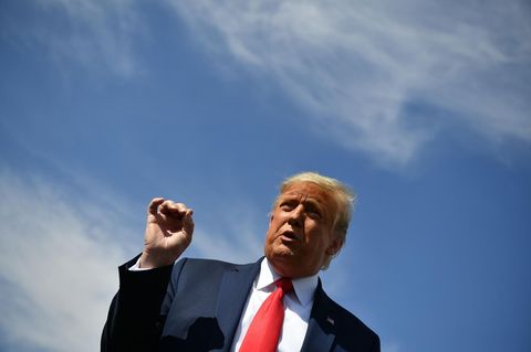 Unter einem blauen Himmel steht US-Präsident Trump an einem Rednerpult und gestikuliert mit der rechten Hand