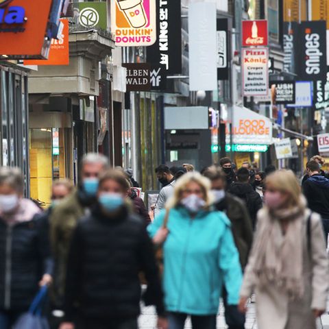 Eine gut besuchten Einkaufsstraße in Köln, viele Menschen tragen eine Maske.