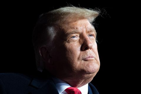 Vor dunklem Hintergrund ist nur das Gesicht von Donald Trump im Licht zu sehen. Schon sein Ohr liegt im Dunkel