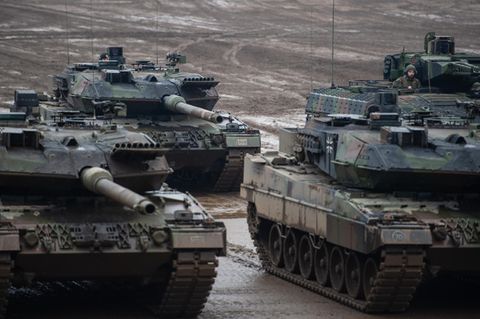Drei Kampfpanzer der Bundeswehr vom Typ Leopard 2A6 und ein Schützenpanzer vom Typ Puma stehen bei einer Übung im Gelände