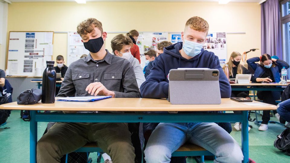 Schüler sitzen in der Klasse mit Schutzmasken