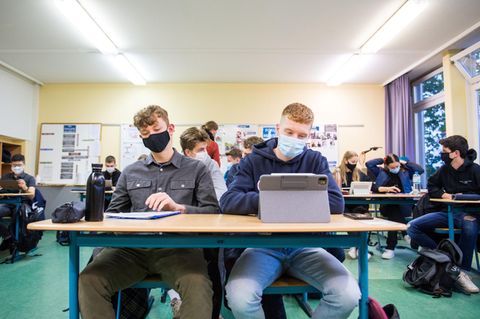 Schüler sitzen in der Klasse mit Schutzmasken