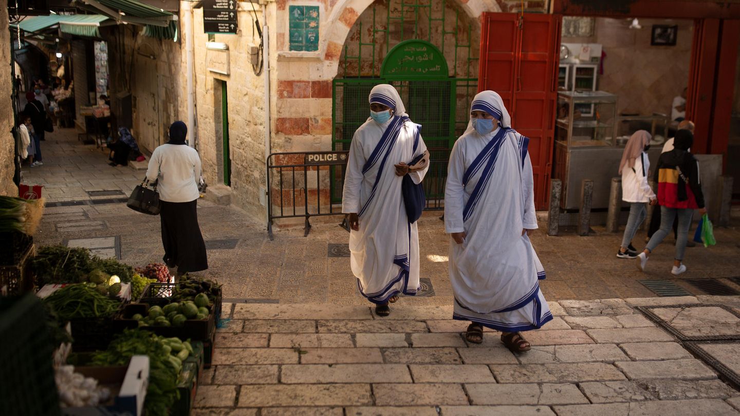 Israel, Jerusalem: Katholische Nonnen gehen mit Mund-Nasen-Schutz über einen Platz in der Altstadt von Jerusalem