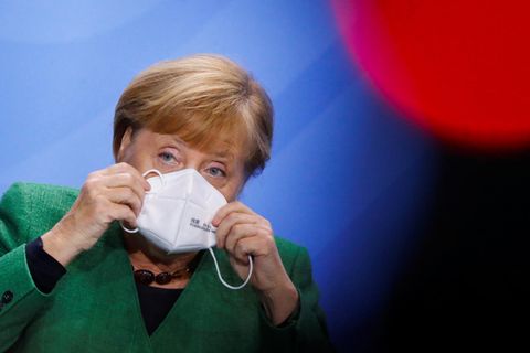Angela Merkel setzt sich eine Maske auf
