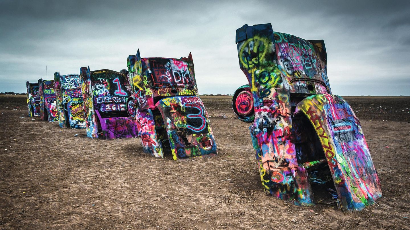 USA: Amarillo  Diese aus dem Boden ragenden alten Straßenkreuzer sind ein berühmtes Kunstwerk, das 1974 neben der Route 66 in Texas errichtet wurde. Im Laufe der Zeit sind die Karosserien immer wieder übersprüht worden.