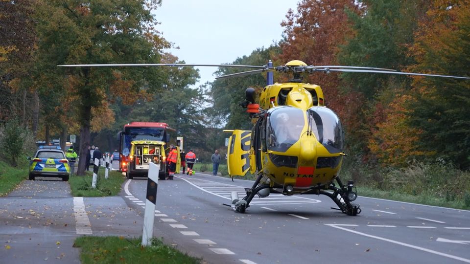Ein Rettungshubschrauber steht auf einer Straße, im Hintergrund ein Polizeiwagen und ein Schulbus.