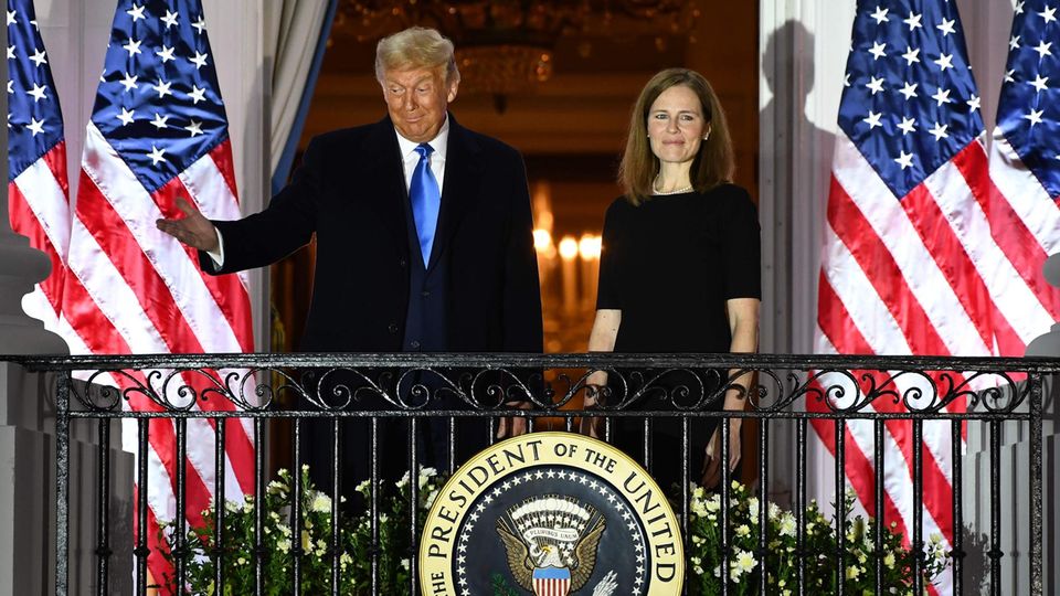 Donald Trump und Amy Coney Barrett vor US-Flaggen auf dem Balken des Weißen Hauses
