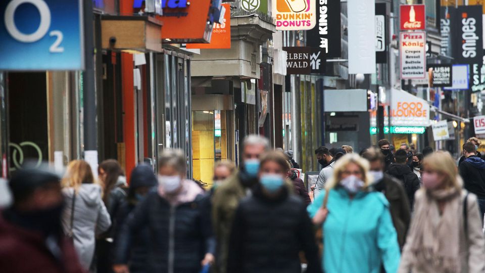 Nordrhein-Westfalen, Köln: Menschen gehen mit Schutzmasken durch die Fußgängerzone
