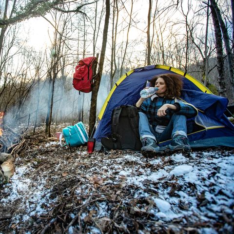 Eine Frau sitzt in ihrem Zelt im Wald