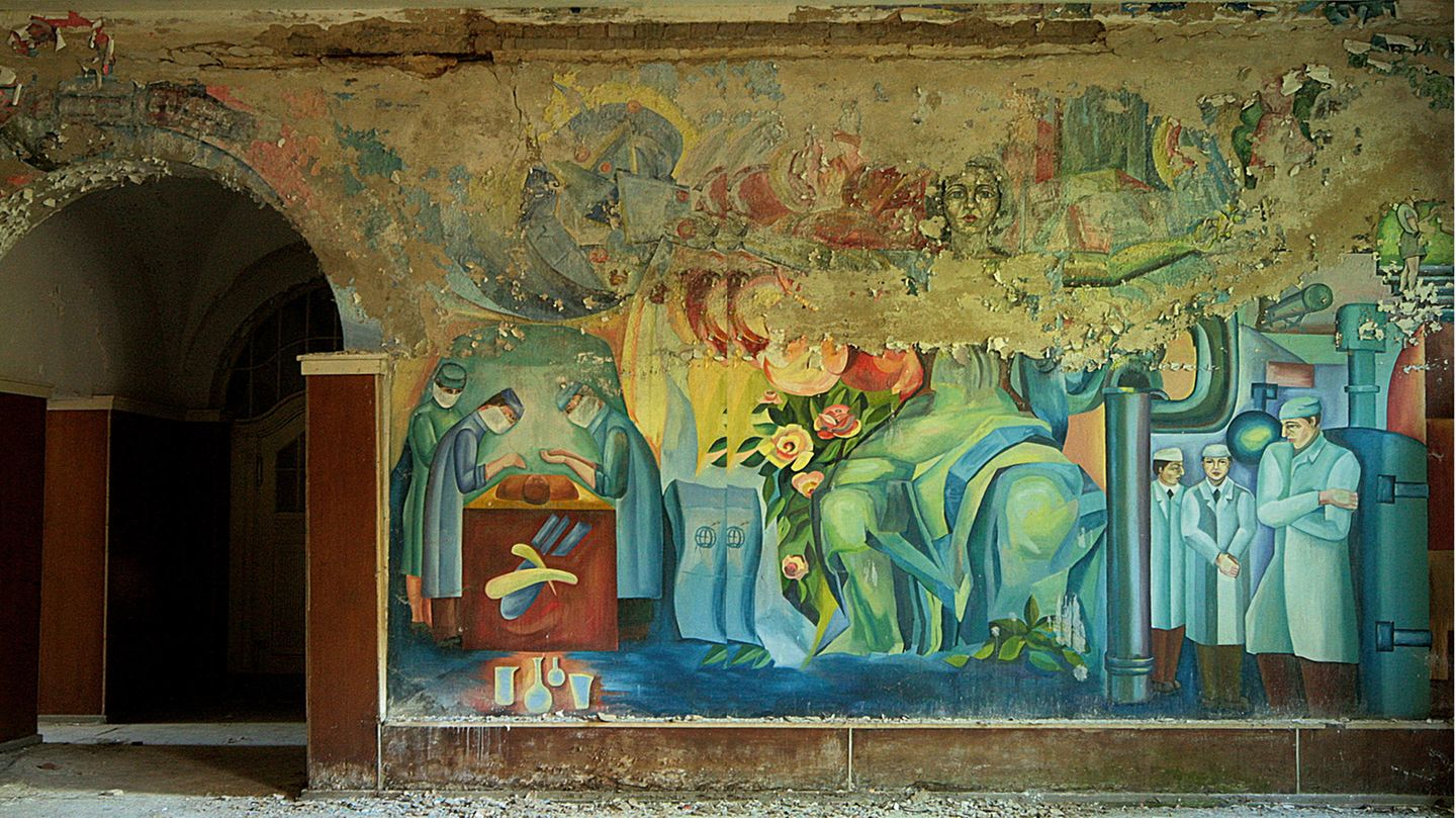 Lost Places: Landesanstalt Teupitz Ein Wandbild aus sozialistischen Zeiten: Die Anfang des 20. Jahrhunderts errichtete Nervenheilanstalt ist ein Ort zum Gruseln. Denn neben der Funktion als Lazarett in beiden Weltkriegen, wurden hier im Dritten Reich Hunderte Menschen mit Behinderungen eingeliefert, die im Rahmen des Euthanasieprogramm der Nazis ermordet worden. Ein Teil der Anlage gehört heute zu den Asklepios Kliniken, der Rest verfällt. Landesanstalt Teupitz Ein Wandbild aus sozialistischen Zeiten: Die Anfang des 20. Jahrhunderts errichtete Nervenheilanstalt ist ein Ort zum Gruseln. Denn neben der Funktion als Lazarett in beiden Weltkriegen, wurden hier im Dritten Reich Hunderte Menschen mit Behinderungen eingeliefert, die im Rahmen des Euthanasieprogramm der Nazis ermordet worden. Ein Teil der Anlage gehört heute zu den Asklepios Kliniken, der Rest verfällt.