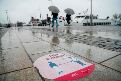 Ein Aufkleber im verregneten Stockholm weißt auf Abstandsregeln