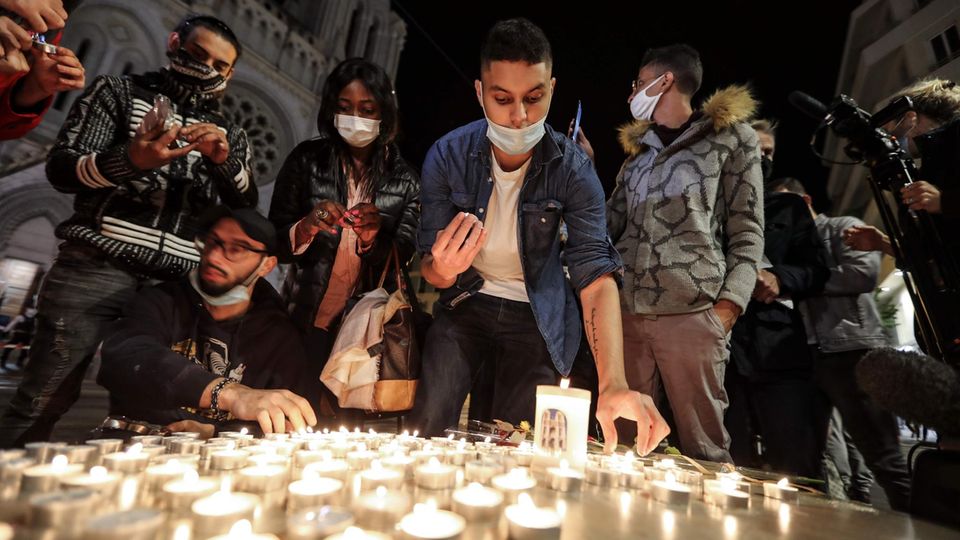Menschen zünden Kerzen auf der Straße vor der Kirche Notre Dame für die Opfer einer Messerattacke an