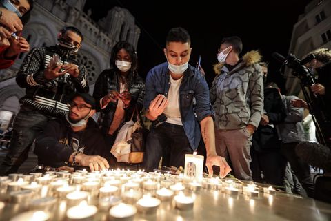 Menschen zünden Kerzen auf der Straße vor der Kirche Notre Dame für die Opfer einer Messerattacke an