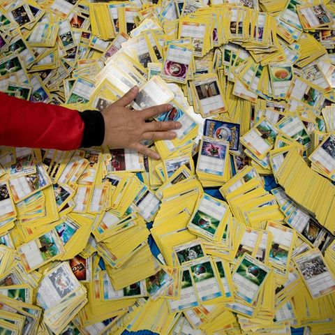 Eine Hand streicht über einen von Pokémon-Karten bedeckten Boden.