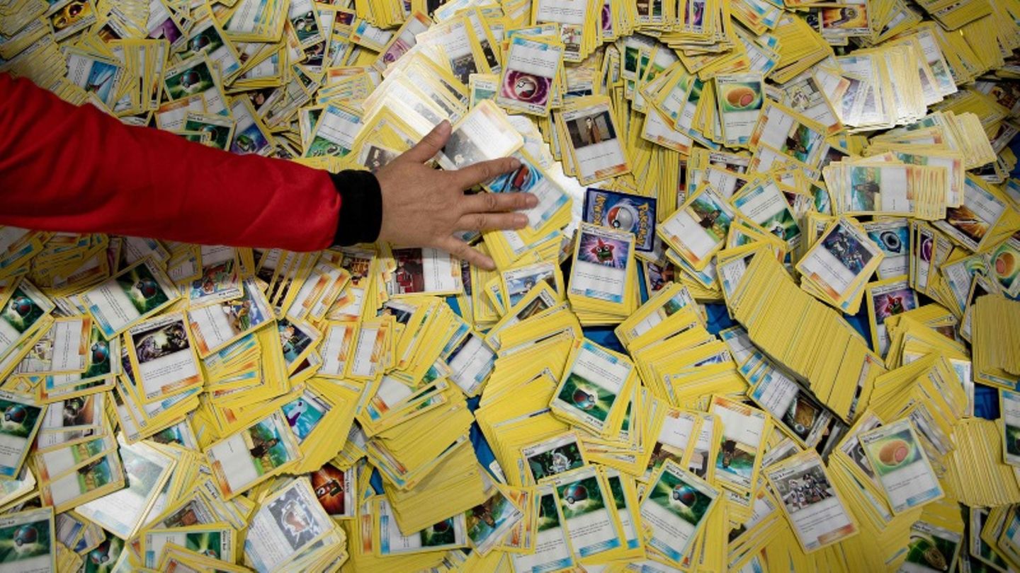 Eine Hand streicht über einen von Pokémon-Karten bedeckten Boden.