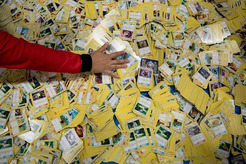 Eine Hand streicht über einen von Pokémon-Karten bedeckten Boden.