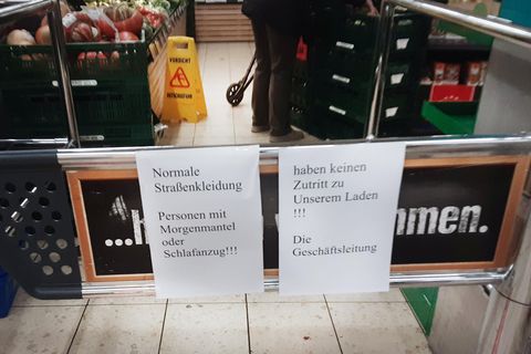 Papierschilder weisen auf ein Verbot von Schlafanzügen im Edeka-Markt hin