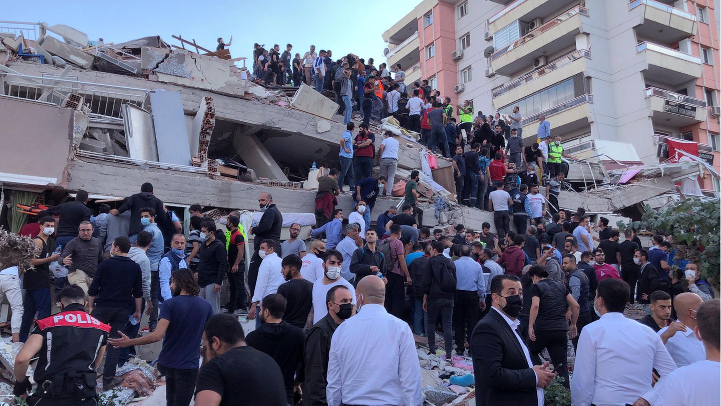 Menschen auf den Trümmern eines durch ein Erdbeben eingestürztes Haus in Izmir