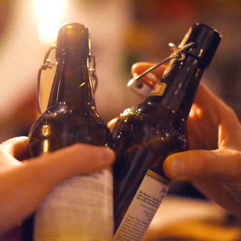 Zwei Hände stoßen mit Bierflaschen an