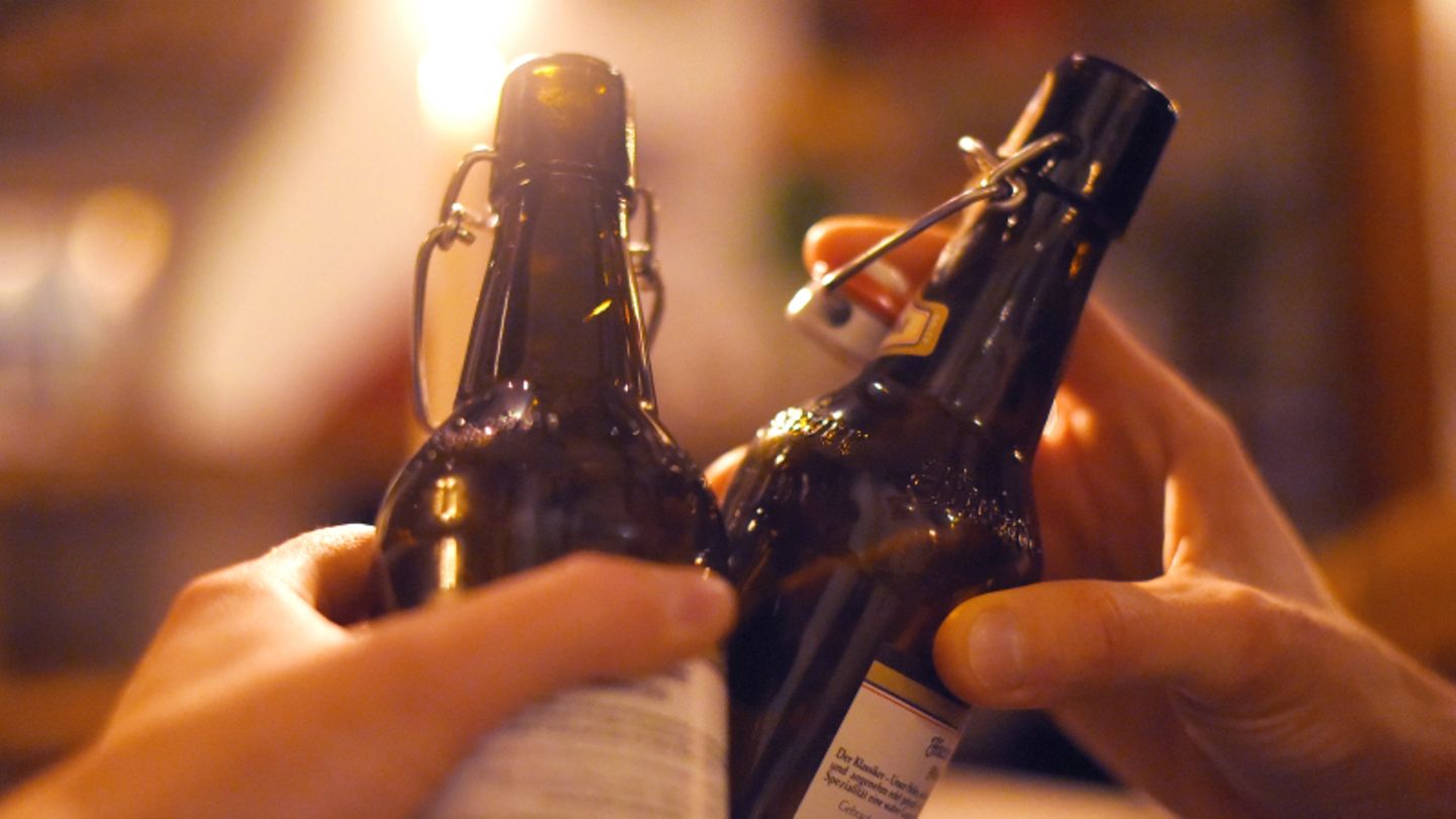 Zwei Hände stoßen mit Bierflaschen an