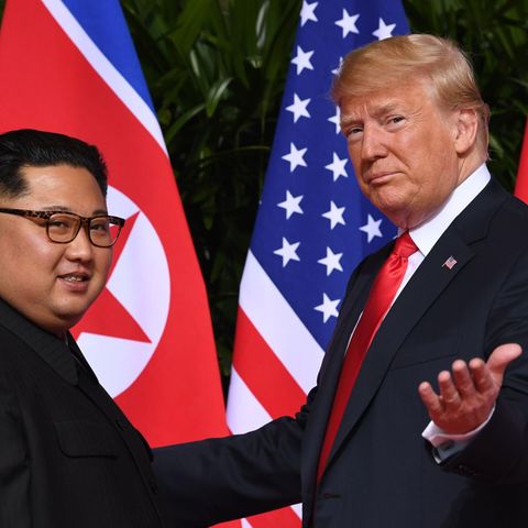Vor den Flaggen der USA und Nordkoreas stehen Kim Jong Un links und Donald Trump rechts
