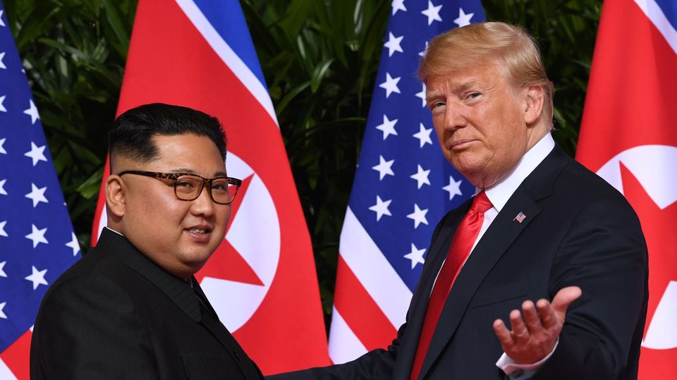 Vor den Flaggen der USA und Nordkoreas stehen Kim Jong Un links und Donald Trump rechts