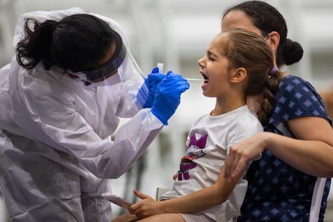 Coronavirus: Eine medizinische Mitarbeiterin in Schutzausrüstung nimmt einen Abstrich bei einem Mädchen