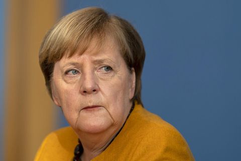 Bundeskanzlerin Angela Merkel im senfgelben Jacket schaut besorgt