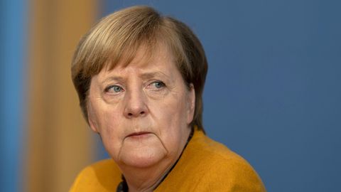 Bundeskanzlerin Angela Merkel im senfgelben Jacket schaut besorgt