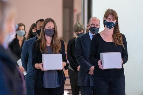 Zwei Frauen tragen Schachteln mit Maoriköpfen zur Übergabe