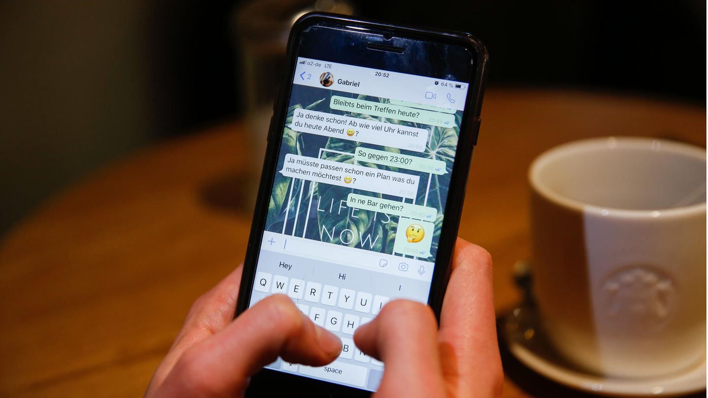 Ein junger Mann benutzt den Messengerdienst Whatsapp auf seinem Handy und schreibt.