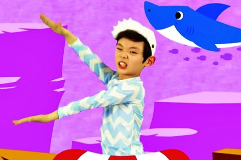 Ein Kind tanzt den Baby Shark-Tanz im Originalvideo, vor einem pinken Hintergrund