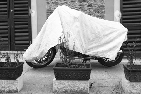 Eine Plane schützt das Motorrad im Freien