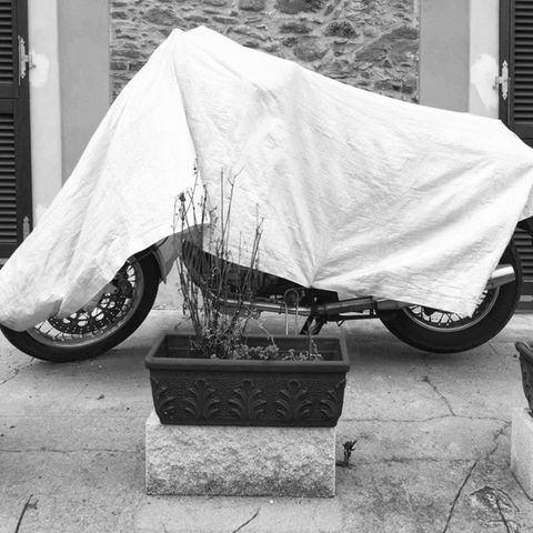 Eine Plane schützt das Motorrad im Freien