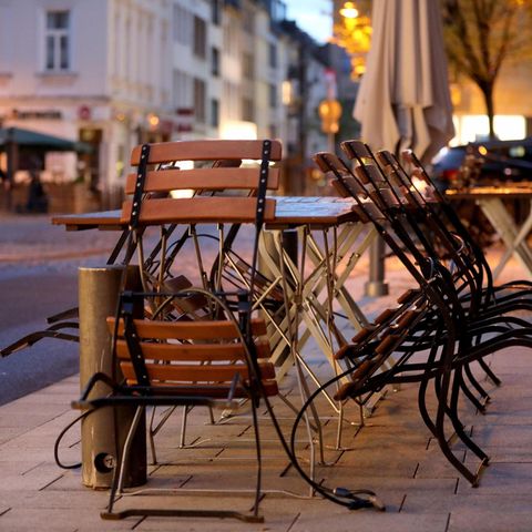 Stühle und Tische sind am Morgen vor einer Gaststätte in Köln zusammengestellt