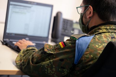 Ein Soldat sitzt vor einem Computer.