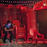 Nach Einbruch der Dunkelheit sammeln afrikanische und asiatische Arbeiter die Strandstühle und Sonnenschirme ein.