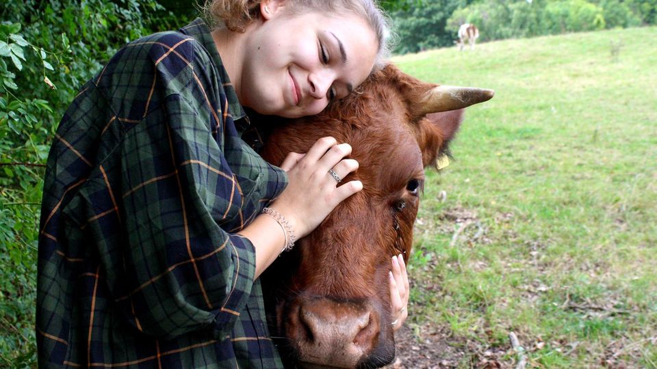 Ein Mädchen kuschelt mit einer Kuh.