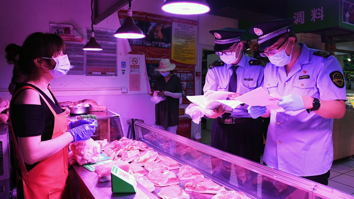 Mitarbeiter der Marktregulierungsverwaltung überprüfen in Peking das Fleisch an einem Marktstand