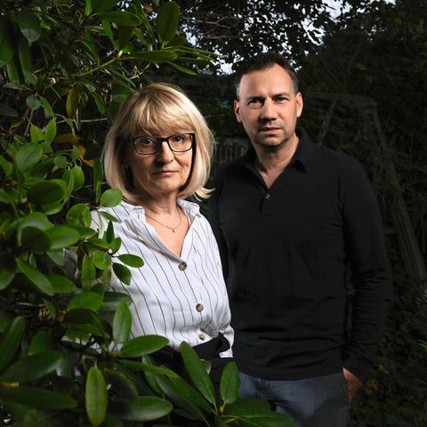 Sabine und Sebastian Fitzek fotografiert vor einer dunklen Hecke