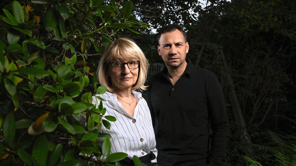 Sabine und Sebastian Fitzek fotografiert vor einer dunklen Hecke